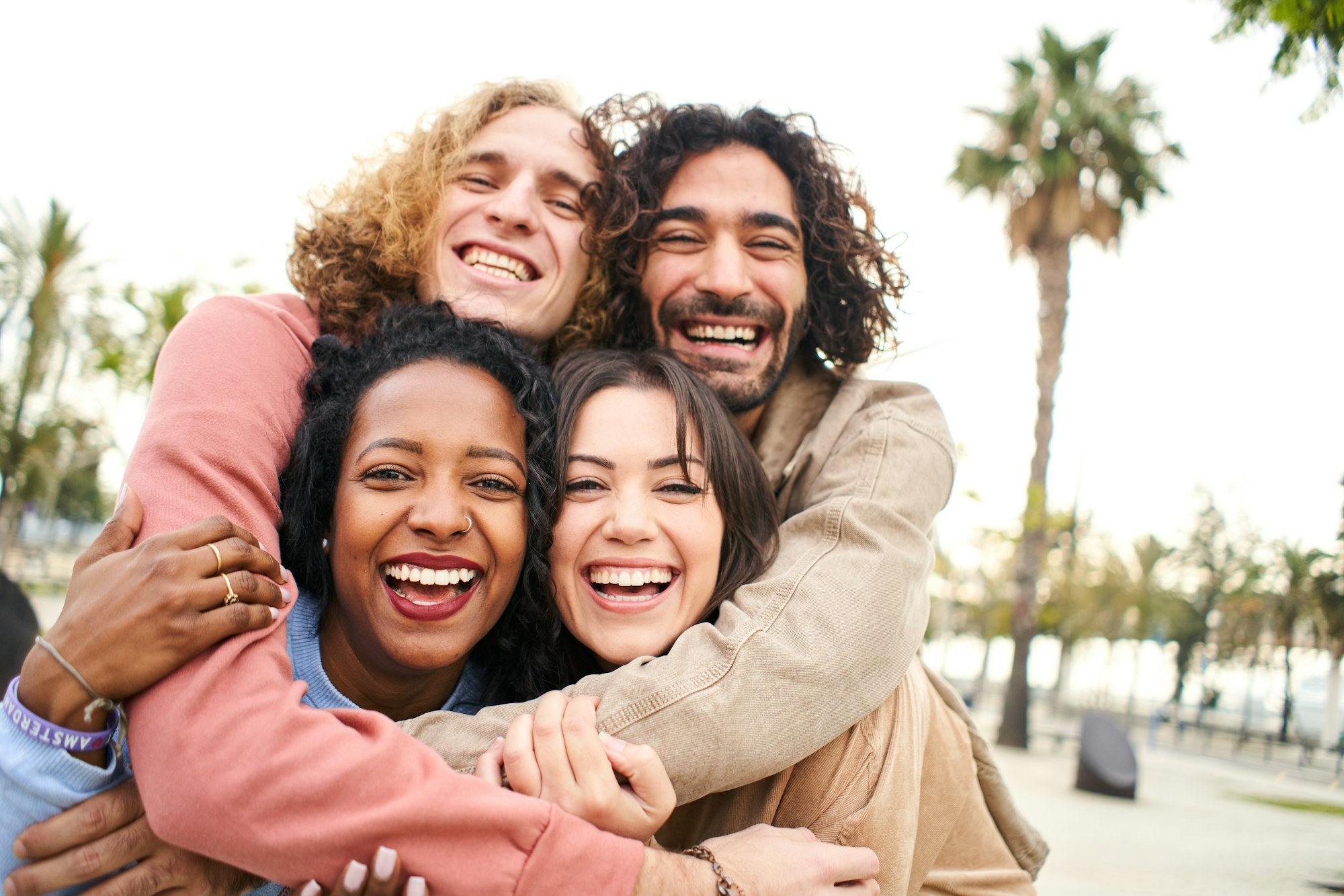 Group of four multi-ethnic young friends having fun. Smiling cheerful people looking at the camera