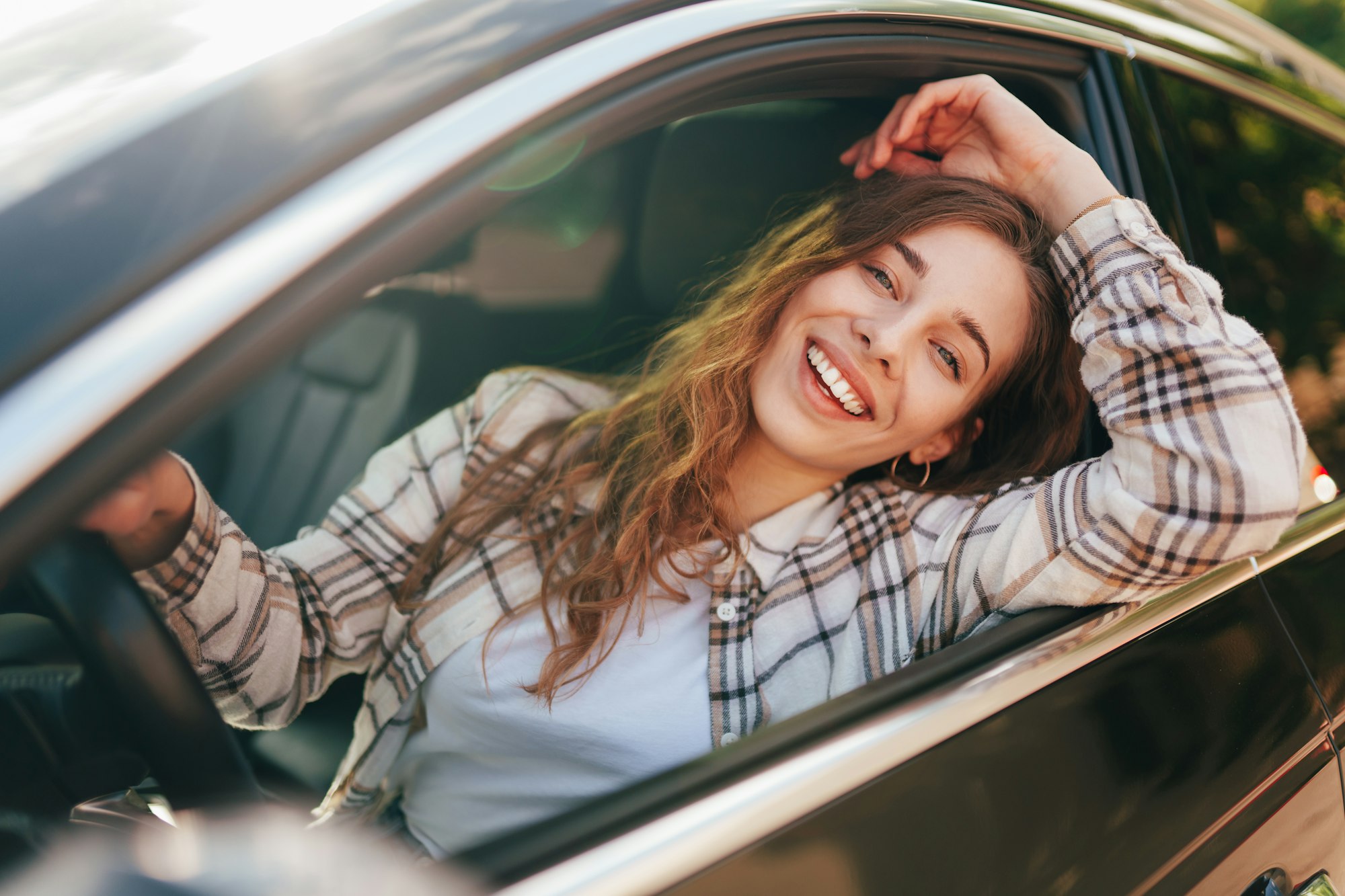 Happy smiling woman inside a car driving in the street