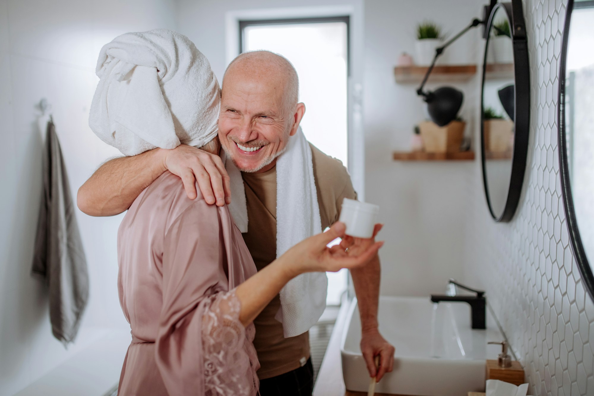 Senior couple in love in bathroom, brushing teeth and hugging, morning routine concept.