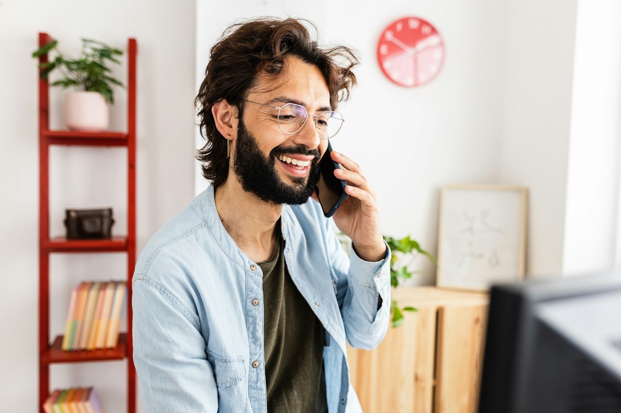 Smiling man talking on the phone while working at home workplace.