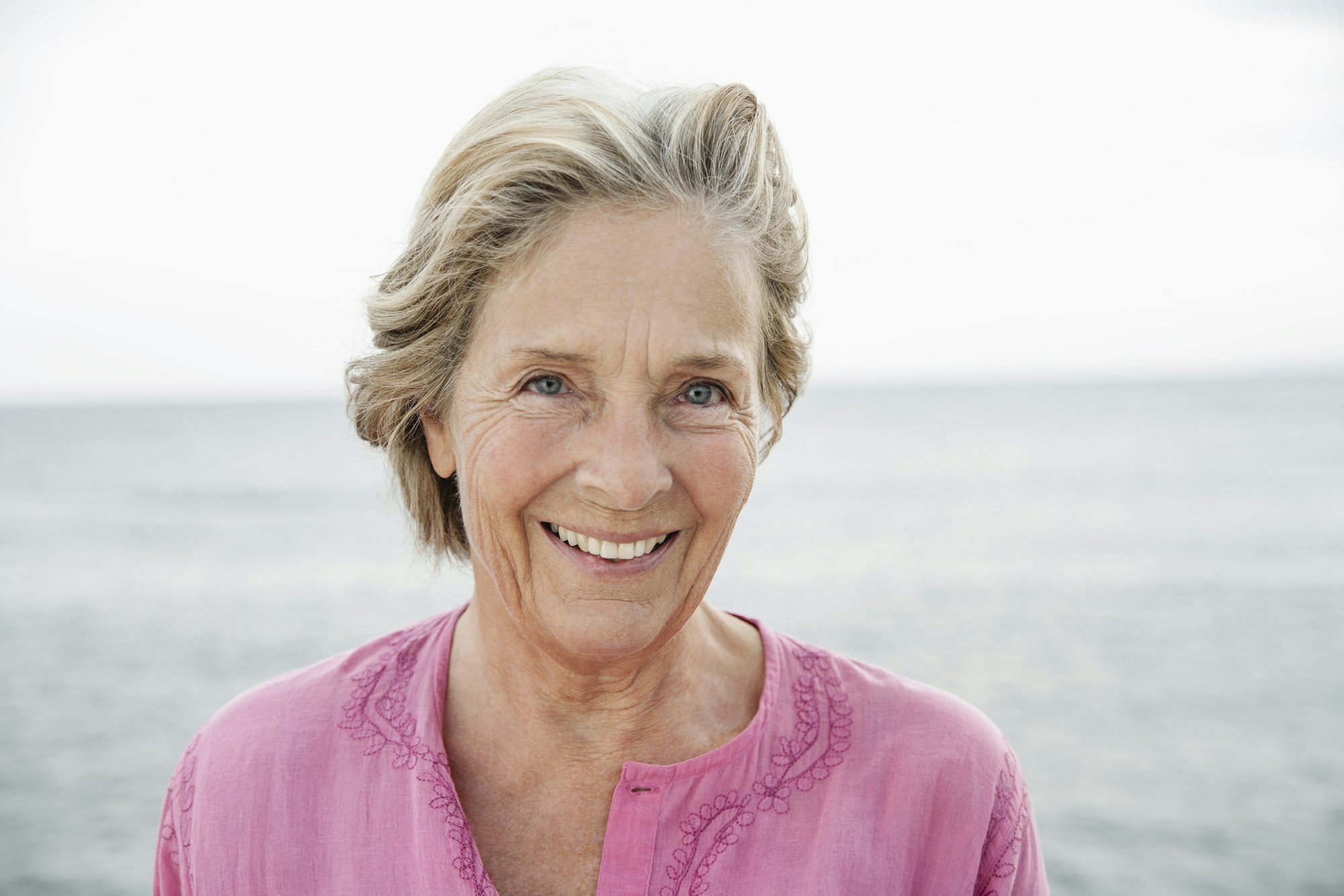 Spain, Senior woman smiling at Atlantic ocean