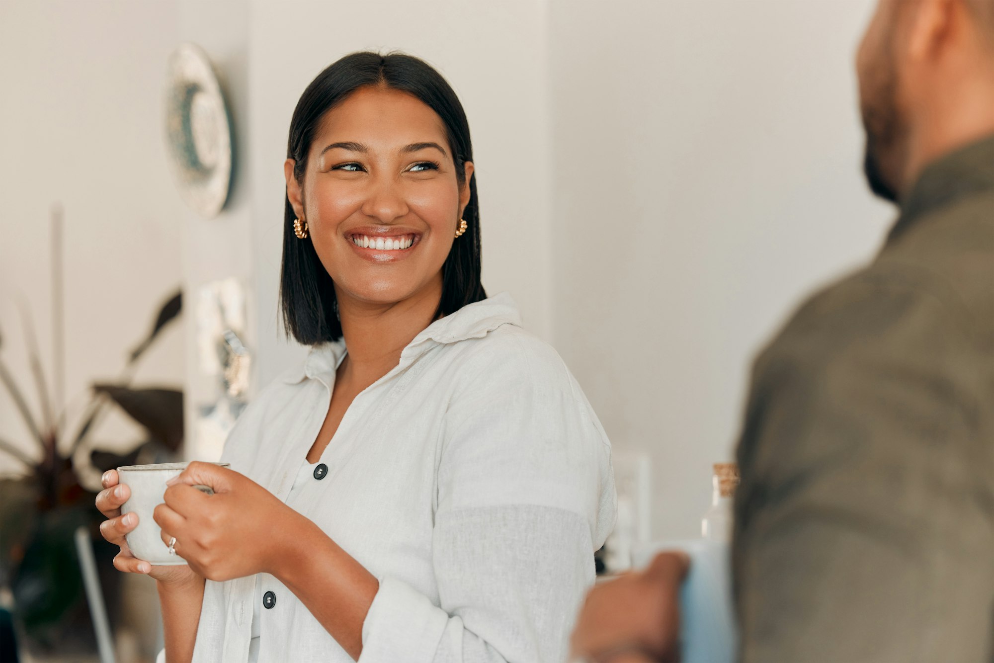 Woman drinking coffee, having conversation and bonding with her husband at home. Smiling, happy and